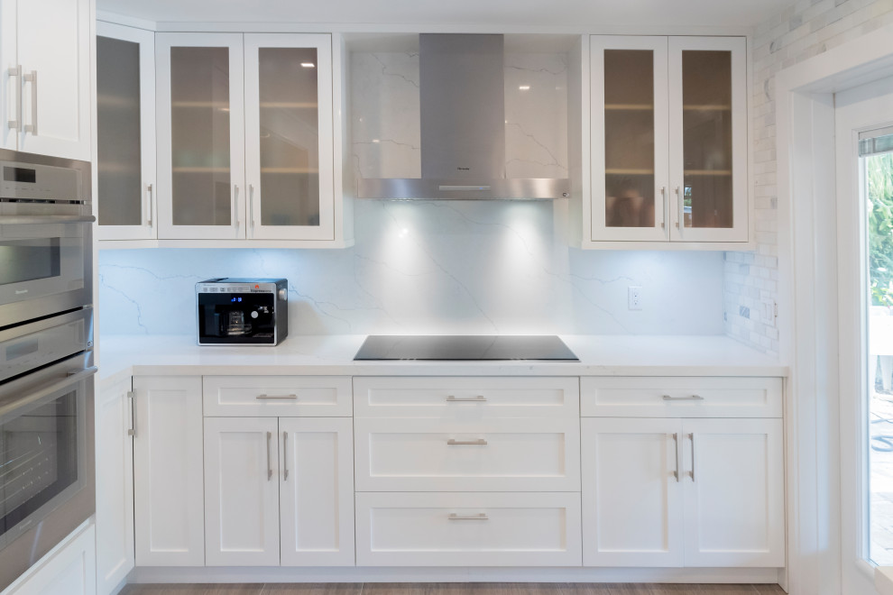 Kitchen pantry - mid-sized transitional galley light wood floor kitchen pantry idea in Miami with an undermount sink, shaker cabinets, white cabinets, quartz countertops, white backsplash, marble backsplash, stainless steel appliances and white countertops