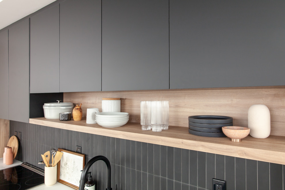 This is an example of a small contemporary galley eat-in kitchen in Toronto with an undermount sink, flat-panel cabinets, white cabinets, laminate benchtops, black splashback, glass tile splashback, stainless steel appliances, laminate floors, with island, brown floor and white benchtop.