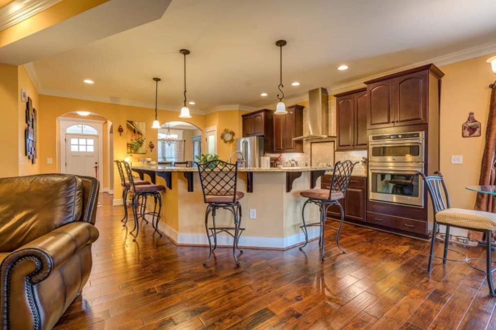 Inspiration for a mid-sized l-shaped medium tone wood floor and brown floor eat-in kitchen remodel with a farmhouse sink, medium tone wood cabinets, granite countertops, an island and multicolored countertops