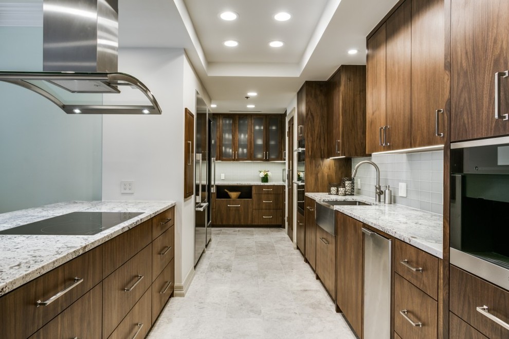 This is an example of a mid-sized contemporary galley separate kitchen in Dallas with a farmhouse sink, flat-panel cabinets, dark wood cabinets, granite benchtops, blue splashback, glass tile splashback, stainless steel appliances, ceramic floors and a peninsula.