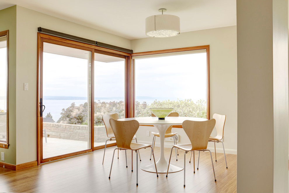 This is an example of a midcentury dining room in Seattle with beige walls and light hardwood floors.