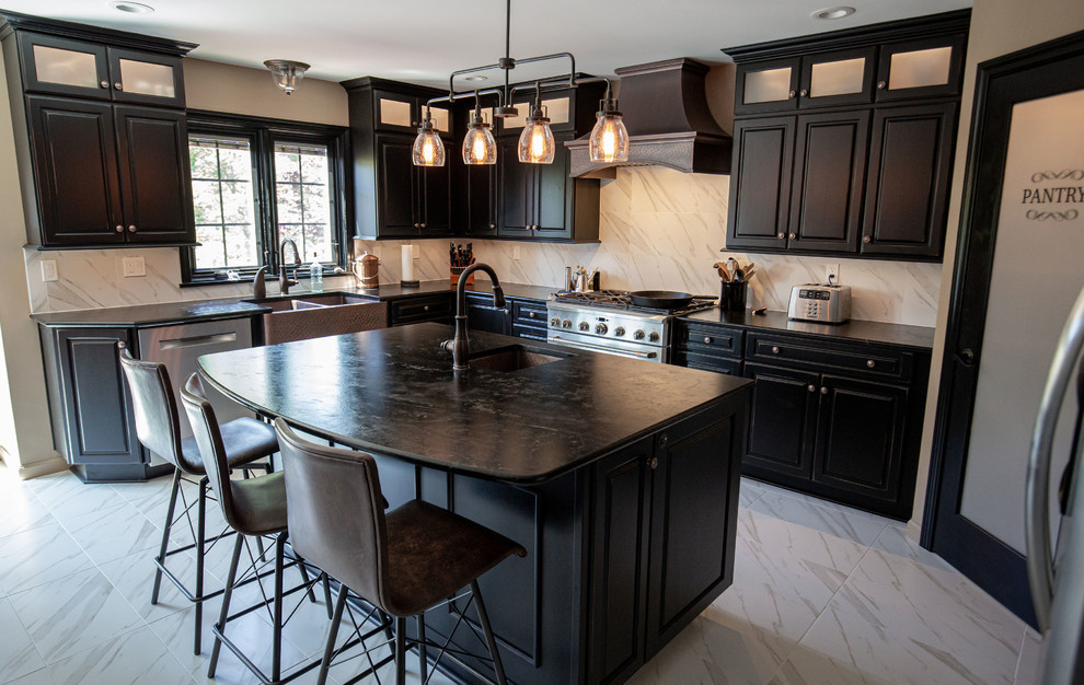This is an example of an expansive industrial u-shaped eat-in kitchen in Boston with a double-bowl sink, raised-panel cabinets, black cabinets, soapstone benchtops, white splashback, porcelain splashback, stainless steel appliances, porcelain floors, with island, white floor and multi-coloured benchtop.