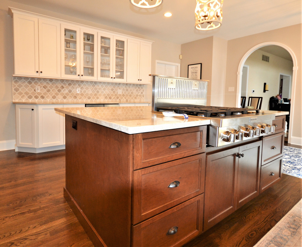 Klassisk inredning av ett stort beige beige kök, med en rustik diskho, luckor med upphöjd panel, vita skåp, bänkskiva i kvartsit, beige stänkskydd, stänkskydd i marmor, rostfria vitvaror, mellanmörkt trägolv, en köksö och brunt golv