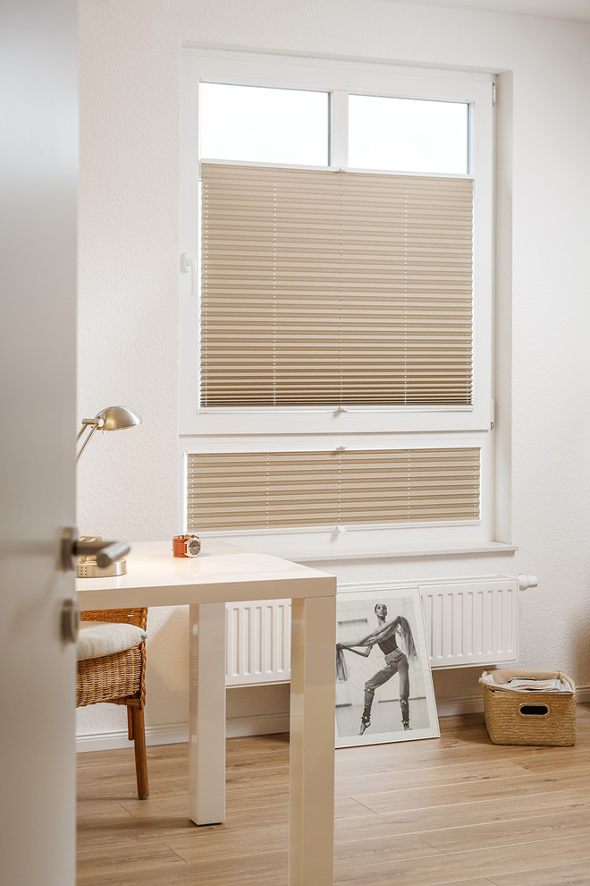 Mittelgroßes Modernes Arbeitszimmer mit Arbeitsplatz, weißer Wandfarbe, braunem Holzboden und freistehendem Schreibtisch in Berlin