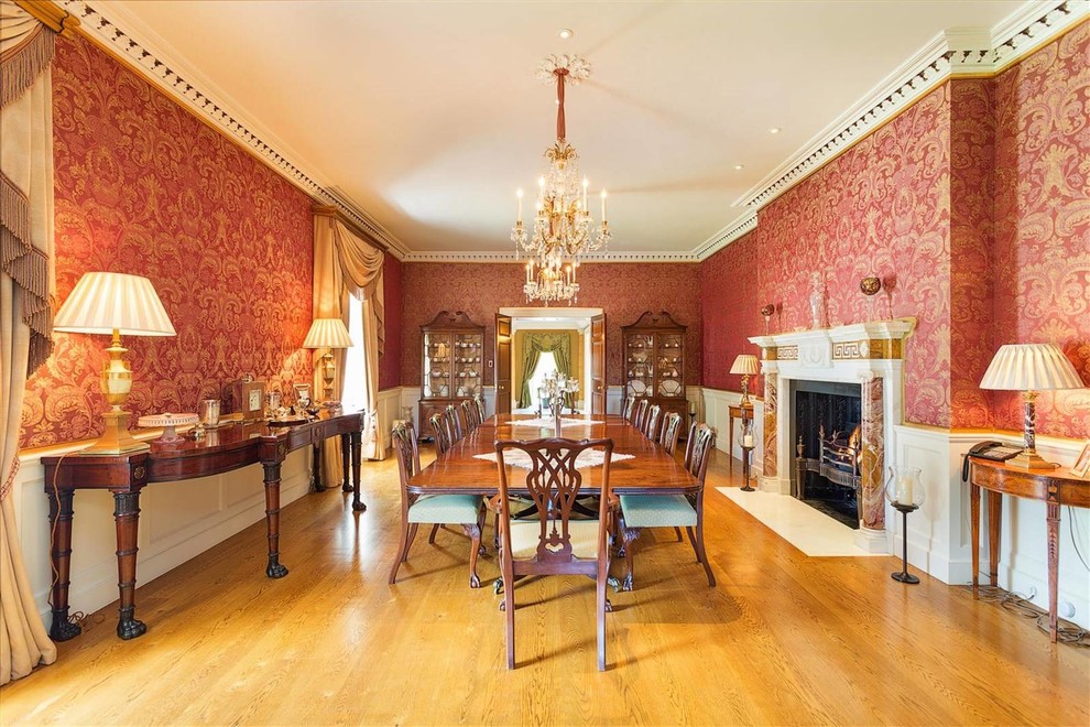 Photo of a large traditional separate dining room in Other with red walls, medium hardwood floors, a standard fireplace and a stone fireplace surround.