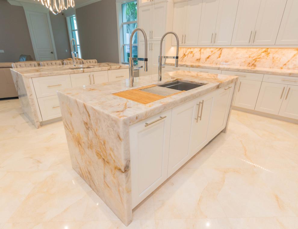 Huge transitional u-shaped marble floor and white floor open concept kitchen photo with an undermount sink, flat-panel cabinets, white cabinets, quartzite countertops, white backsplash, stone slab backsplash and two islands