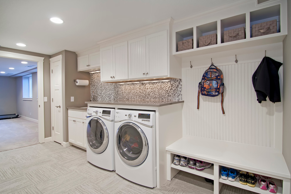 This is an example of a large traditional single-wall utility room in Minneapolis with white cabinets, a side-by-side washer and dryer, an undermount sink, shaker cabinets, solid surface benchtops, ceramic floors, grey floor, beige benchtop and grey walls.