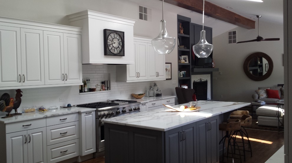 Example of a mid-sized mountain style u-shaped dark wood floor open concept kitchen design in Denver with raised-panel cabinets, white cabinets, marble countertops, white backsplash, subway tile backsplash, stainless steel appliances, an island and an integrated sink