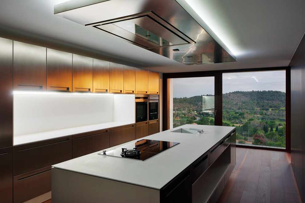 Large contemporary galley separate kitchen in Other with an integrated sink, flat-panel cabinets, white splashback, dark hardwood floors, with island, stainless steel cabinets and solid surface benchtops.