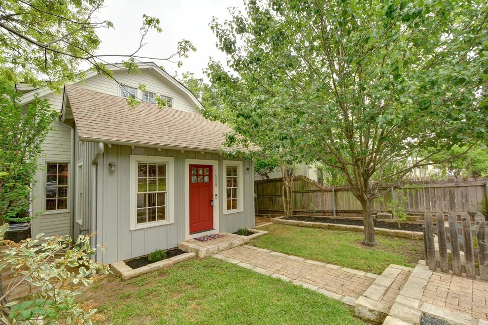 Traditional two-storey grey house exterior in Austin with a gable roof and a shingle roof.