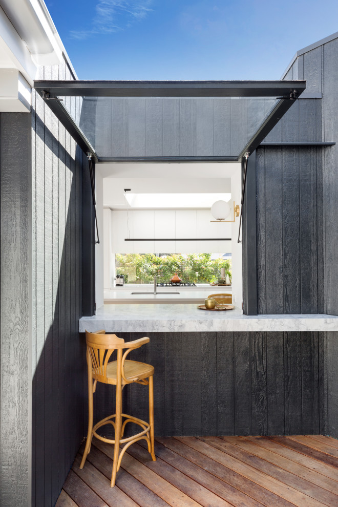 Mid-sized scandinavian one-storey black house exterior in Melbourne with wood siding, a gable roof and a metal roof.