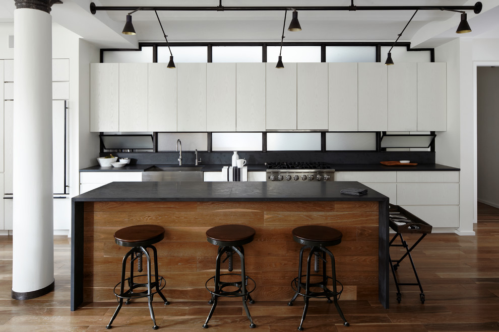 This is an example of a contemporary single-wall open plan kitchen in New York with a farmhouse sink, flat-panel cabinets and white cabinets.