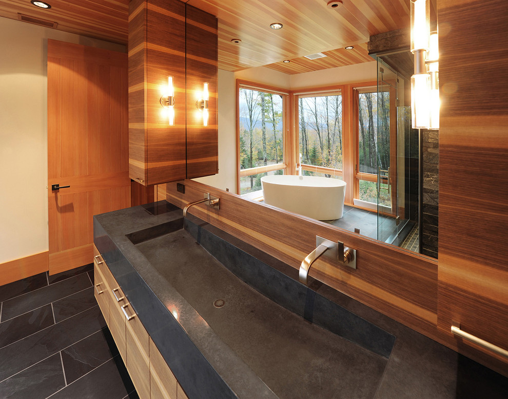 Mid-sized mountain style master black tile and ceramic tile ceramic tile freestanding bathtub photo with flat-panel cabinets, light wood cabinets, beige walls, a trough sink and concrete countertops
