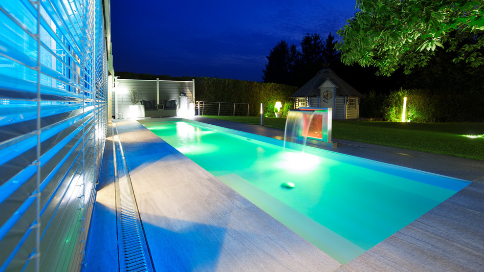 Großes Modernes Sportbecken neben dem Haus in rechteckiger Form mit Wasserspiel und Natursteinplatten in Dortmund