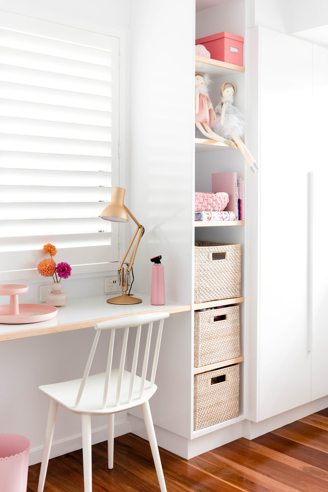 This is an example of a beach style kids' study room for kids 4-10 years old and girls in Brisbane with white walls and medium hardwood floors.