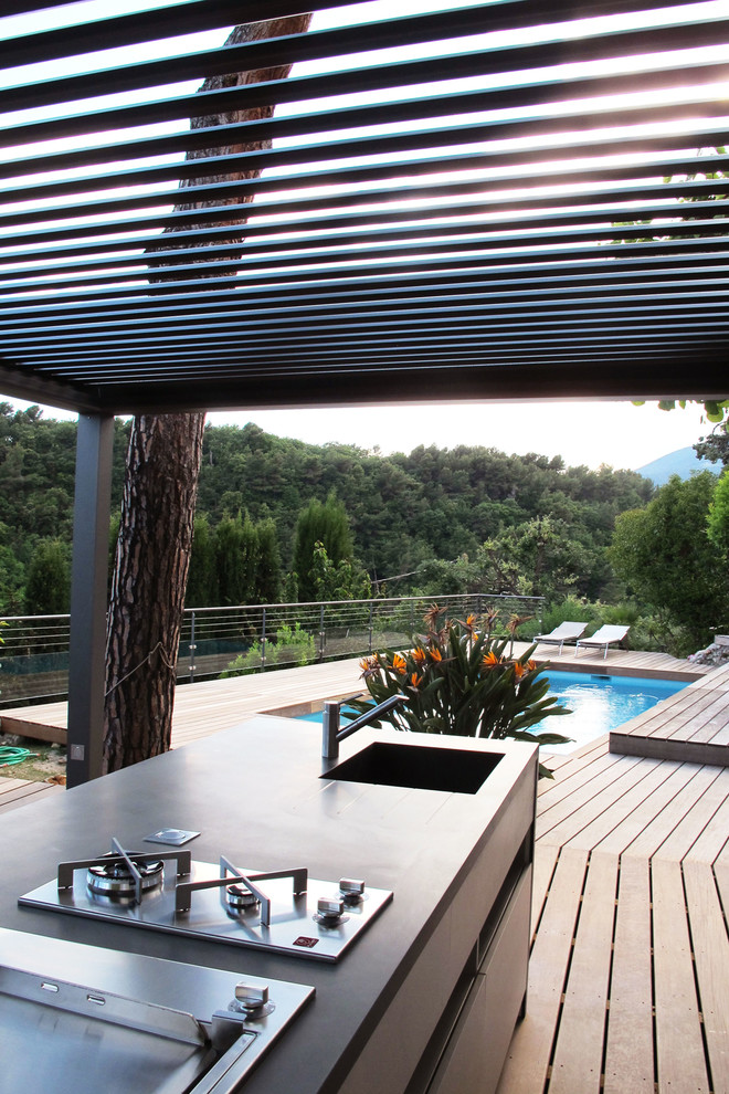 Photo of a large mediterranean backyard deck in Nice with an outdoor kitchen and a pergola.