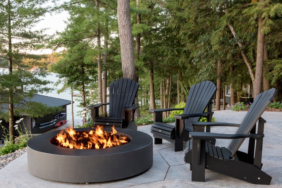 Photo of a mid-sized country backyard patio in Toronto with a fire feature, natural stone pavers and a roof extension.