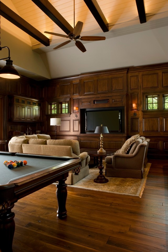 This is an example of a large tropical open concept family room in Charleston with a game room, dark hardwood floors, no fireplace, a built-in media wall, brown floor and beige walls.