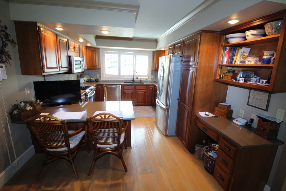 Inspiration for a transitional medium tone wood floor and brown floor kitchen remodel with an undermount sink, raised-panel cabinets, quartz countertops, stainless steel appliances, dark wood cabinets, multicolored backsplash and brown countertops