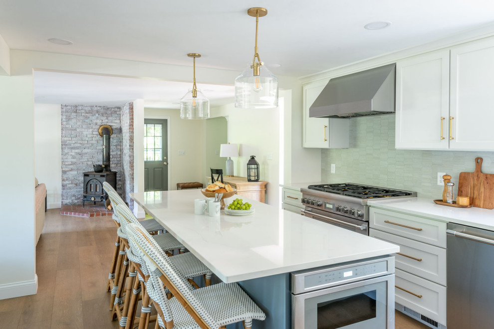 Mid-sized transitional l-shaped light wood floor and brown floor eat-in kitchen photo in Boston with an undermount sink, shaker cabinets, white cabinets, quartz countertops, gray backsplash, ceramic backsplash, stainless steel appliances, an island and white countertops