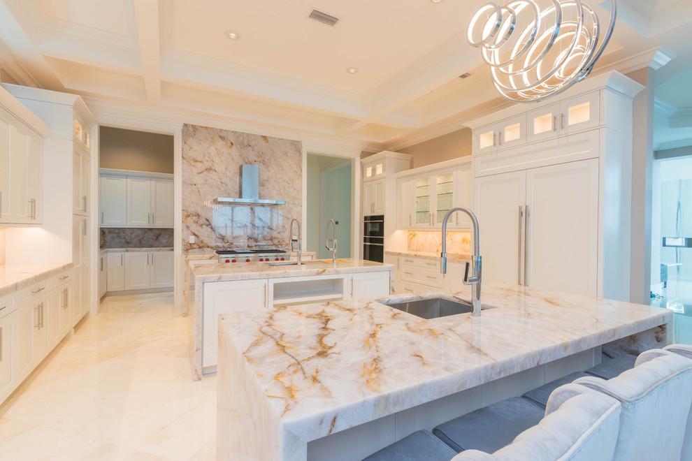 Example of a huge transitional u-shaped marble floor and white floor open concept kitchen design with an undermount sink, flat-panel cabinets, white cabinets, quartzite countertops, white backsplash, stone slab backsplash and two islands