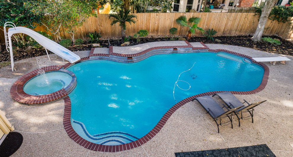 Großer Klassischer Pool hinter dem Haus in Nierenform mit Betonplatten in Houston