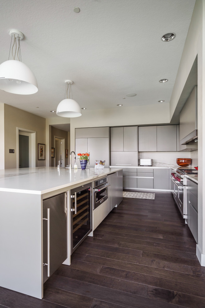 Inspiration for a large contemporary l-shaped open plan kitchen in Portland with an undermount sink, flat-panel cabinets, grey cabinets, quartz benchtops, white splashback, stone slab splashback, panelled appliances, dark hardwood floors, with island, brown floor and white benchtop.