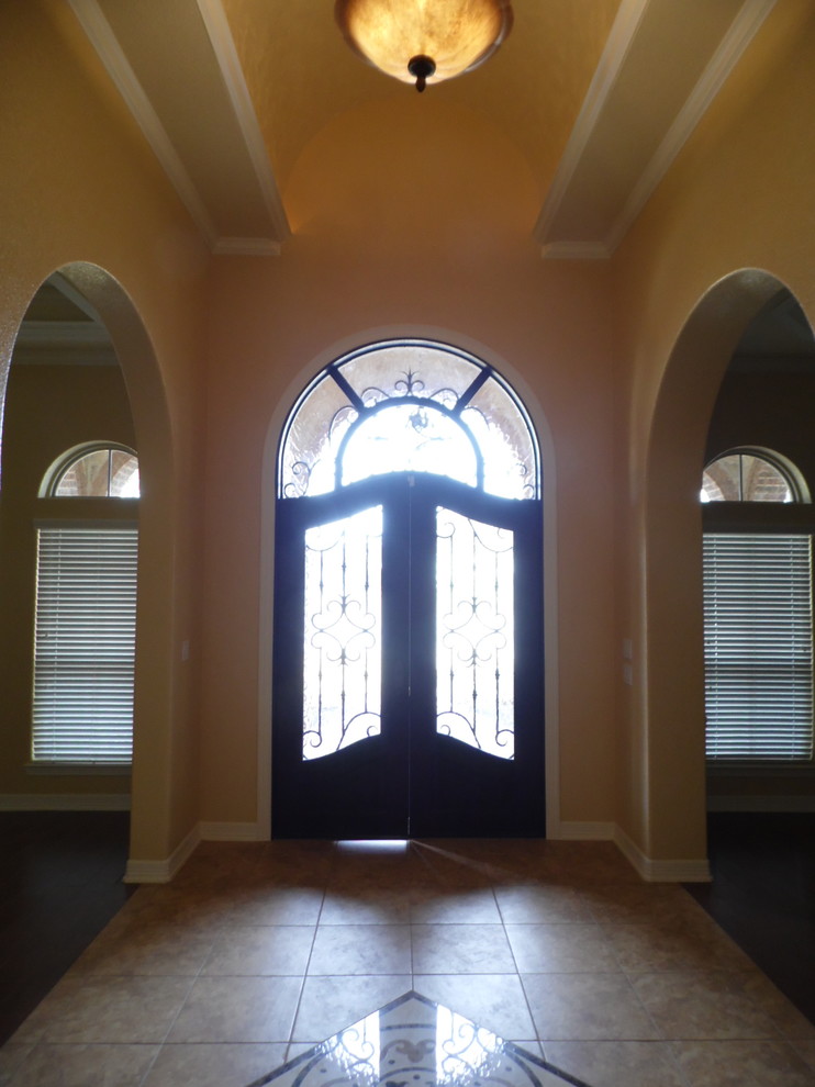 Mid-sized mediterranean foyer in Austin with yellow walls, ceramic floors, a double front door and a metal front door.