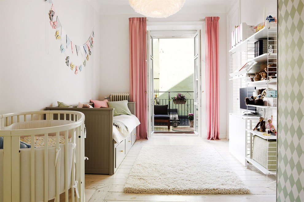 Photo of a mid-sized scandinavian gender-neutral kids' bedroom for kids 4-10 years old in Stockholm with white walls and light hardwood floors.