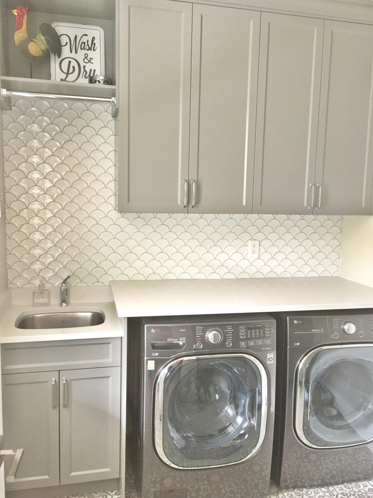 Photo of a country single-wall dedicated laundry room in Vancouver with an undermount sink, flat-panel cabinets, grey cabinets, quartz benchtops, white walls, vinyl floors, a side-by-side washer and dryer, multi-coloured floor and white benchtop.