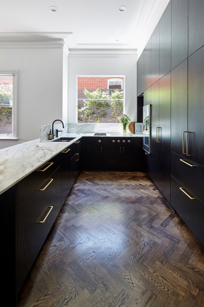 Photo of a mid-sized traditional u-shaped eat-in kitchen in Melbourne with a double-bowl sink, black cabinets, marble benchtops, multi-coloured splashback, marble splashback, stainless steel appliances, medium hardwood floors, with island, brown floor and multi-coloured benchtop.