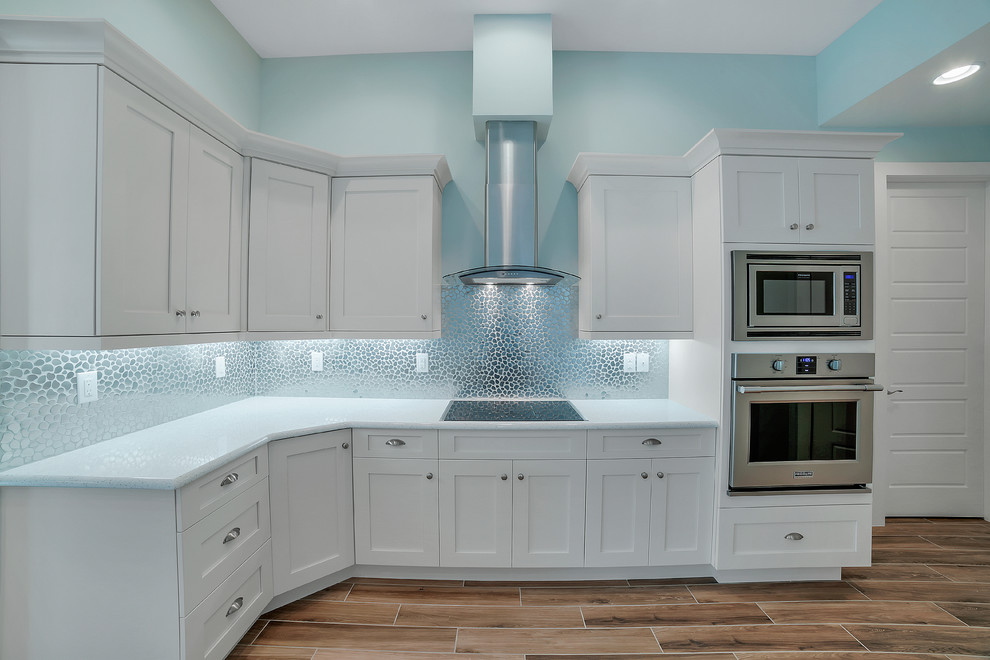 Mid-sized transitional u-shaped open concept kitchen photo with a drop-in sink, recessed-panel cabinets, white cabinets, quartzite countertops, multicolored backsplash, mosaic tile backsplash, stainless steel appliances and an island