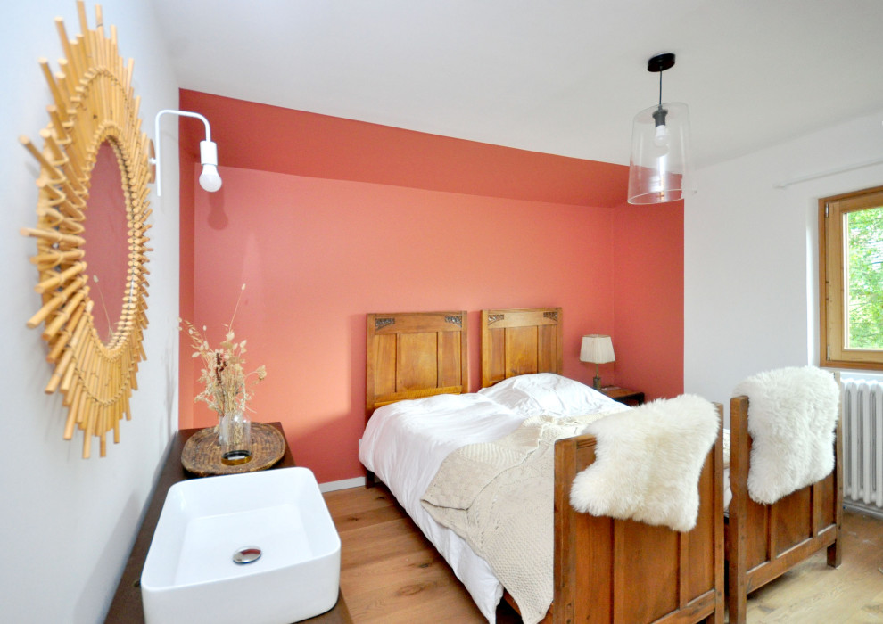 Cette image montre une chambre chalet avec un mur orange et parquet clair.