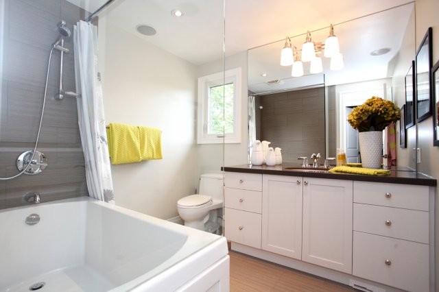 Tub/shower combo - mid-sized transitional 3/4 gray tile and ceramic tile ceramic tile and brown floor tub/shower combo idea in Toronto with an undermount sink, white cabinets, white walls, shaker cabinets, a two-piece toilet and quartz countertops