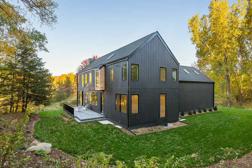Diseño de fachada de casa negra y negra escandinava grande de dos plantas con revestimiento de madera, tejado a dos aguas, tejado de teja de madera y panel y listón