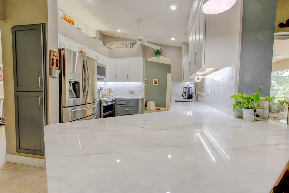 Inspiration for a mid-sized contemporary galley kitchen pantry remodel with an undermount sink, shaker cabinets, white cabinets, quartz countertops, white backsplash, stone slab backsplash, stainless steel appliances, a peninsula and white countertops