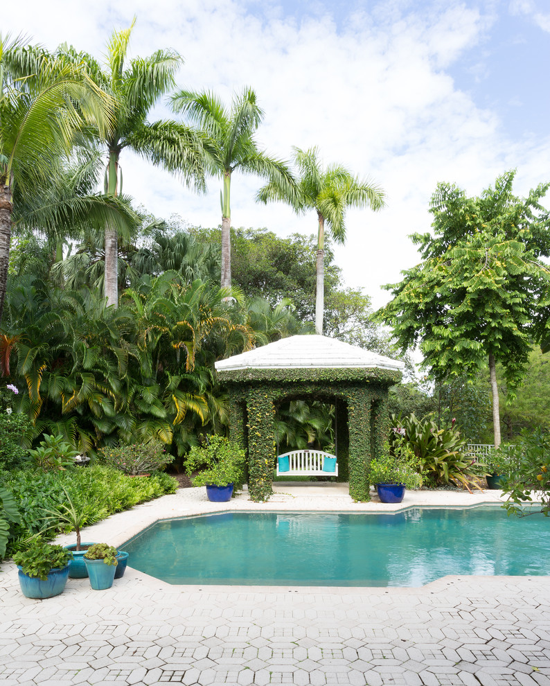 Photo of a tropical custom-shaped pool in Miami with concrete pavers.