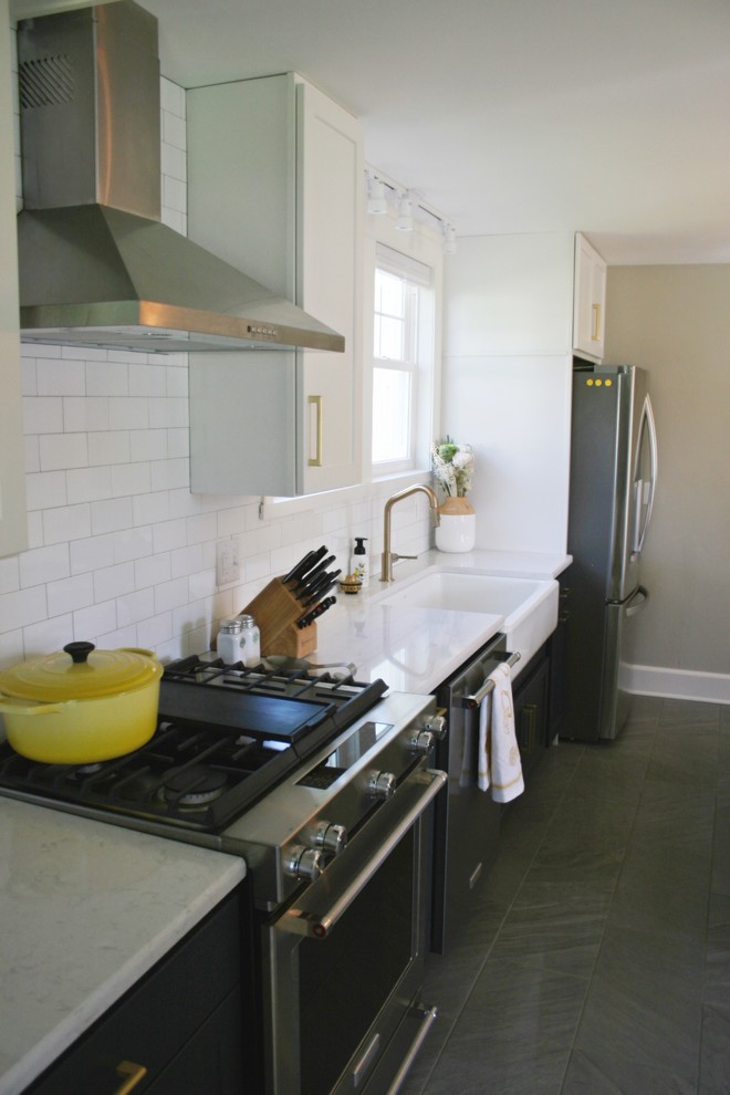 Example of a transitional gray floor kitchen design with a farmhouse sink, quartz countertops and stainless steel appliances