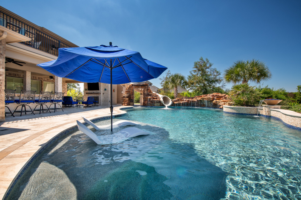 Inspiration for a large traditional backyard custom-shaped pool in Houston with a water slide and natural stone pavers.