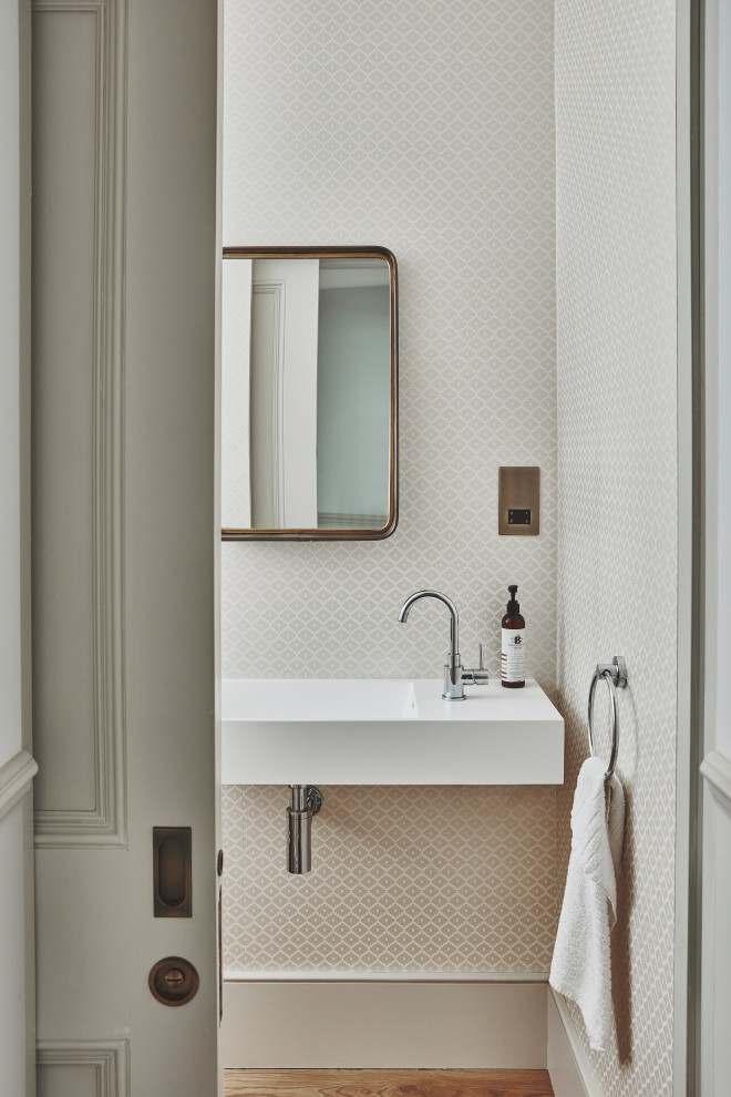 Photo of a small modern cloakroom in London with beige walls, light hardwood flooring and a wall-mounted sink.