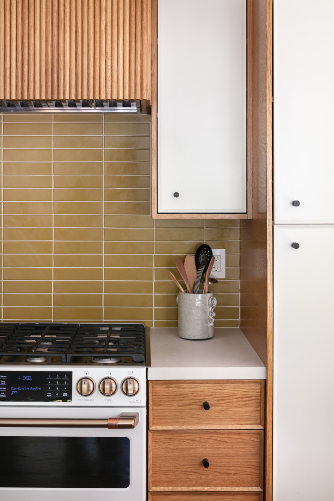 Foto på ett stort 50 tals vit kök, med en rustik diskho, luckor med profilerade fronter, skåp i ljust trä, bänkskiva i kvarts, grönt stänkskydd, stänkskydd i porslinskakel, rostfria vitvaror, betonggolv, en köksö och brunt golv
