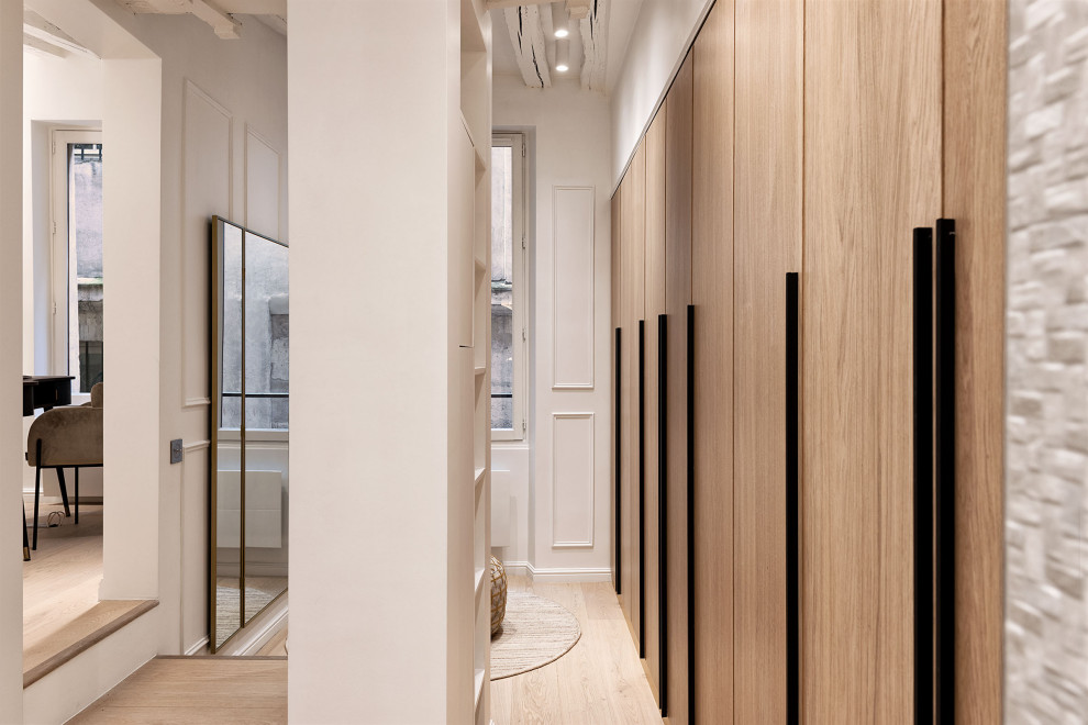 Großes Modernes Ankleidezimmer mit Ankleidebereich, hellen Holzschränken, hellem Holzboden und freigelegten Dachbalken in Paris