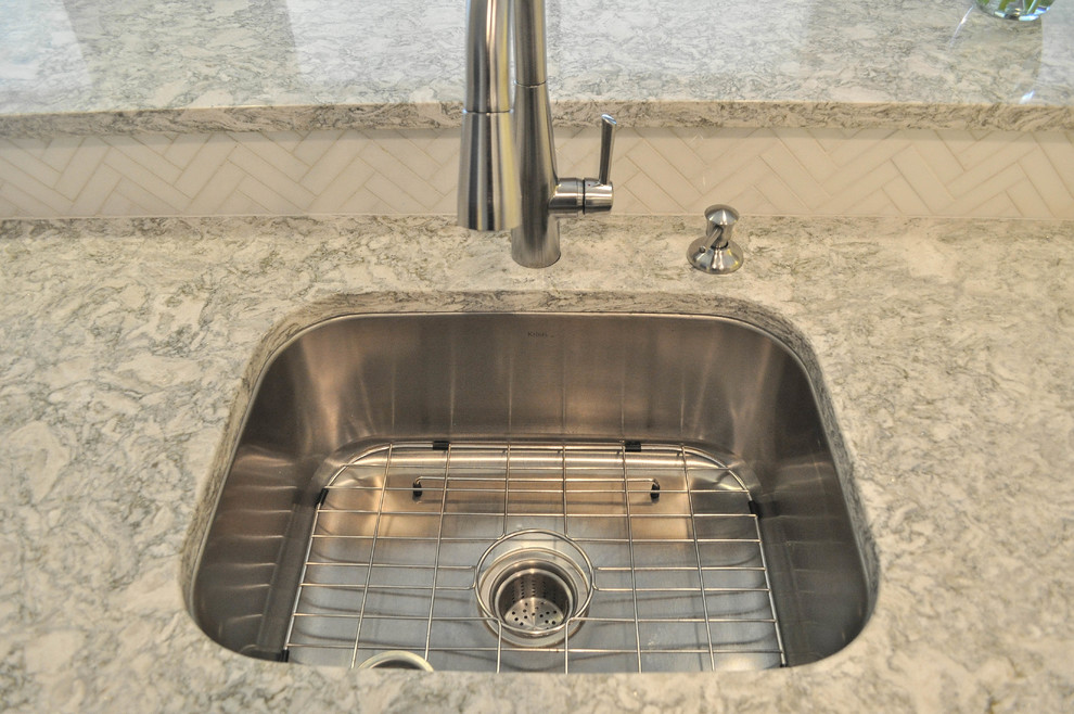 Example of a mid-sized transitional u-shaped eat-in kitchen design with an undermount sink, shaker cabinets, white cabinets, quartz countertops, white backsplash, marble backsplash, stainless steel appliances and no island