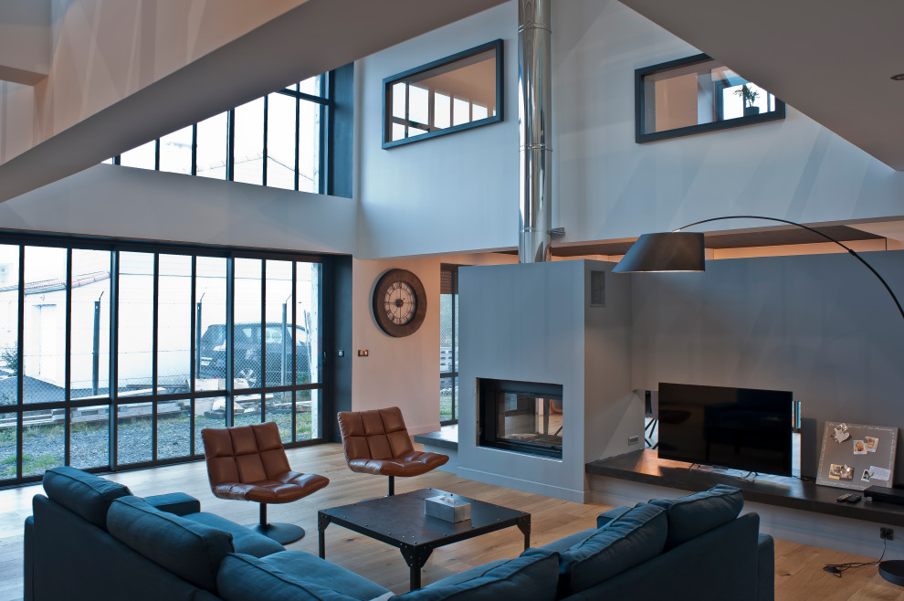 Inspiration for a large contemporary open concept living room in Nantes with grey walls, light hardwood floors, a standard fireplace and a concrete fireplace surround.
