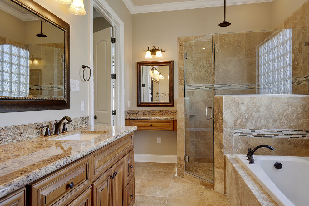 Photo of a mid-sized traditional master bathroom in New Orleans with beaded inset cabinets, brown cabinets, a drop-in tub, a corner shower, brown tile, travertine, beige walls, marble floors, an undermount sink, granite benchtops, beige floor, a hinged shower door and brown benchtops.