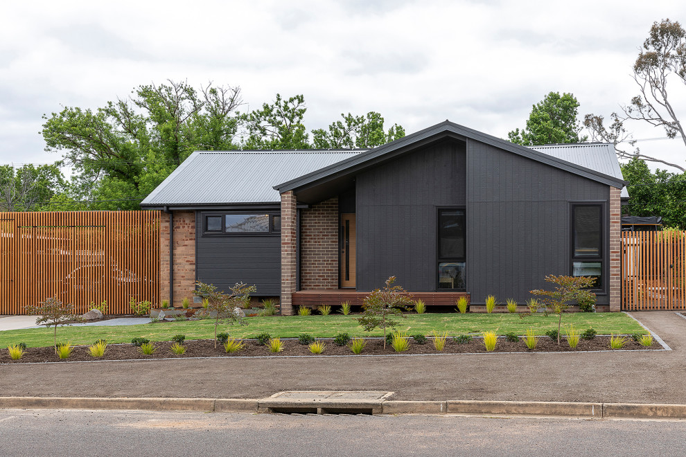 Modelo de fachada de casa negra contemporánea pequeña de una planta con tejado a dos aguas y tejado de metal