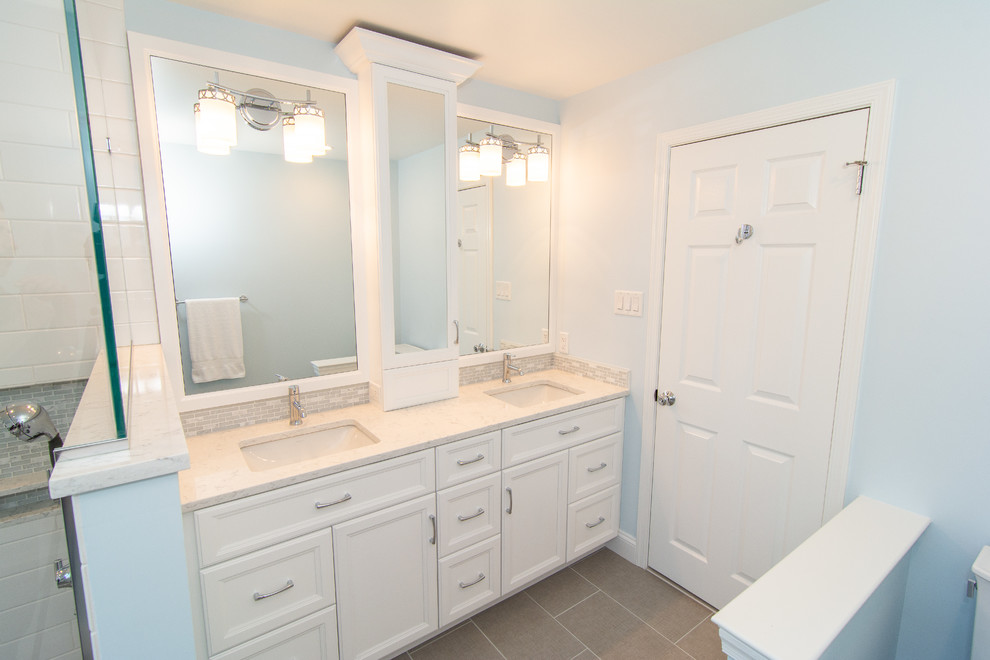 Inspiration for a mid-sized transitional master bathroom in Philadelphia with flat-panel cabinets, white cabinets, a corner shower, a two-piece toilet, white tile, ceramic tile, blue walls, porcelain floors, an undermount sink, engineered quartz benchtops, grey floor, a hinged shower door and white benchtops.