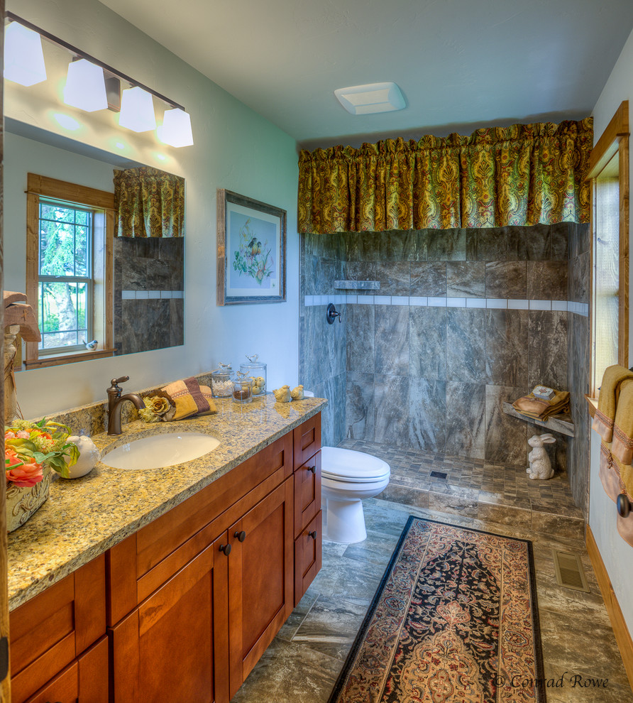 Example of a mid-sized mountain style master multicolored tile and ceramic tile ceramic tile alcove shower design with recessed-panel cabinets, medium tone wood cabinets, a one-piece toilet, white walls, an undermount sink and granite countertops