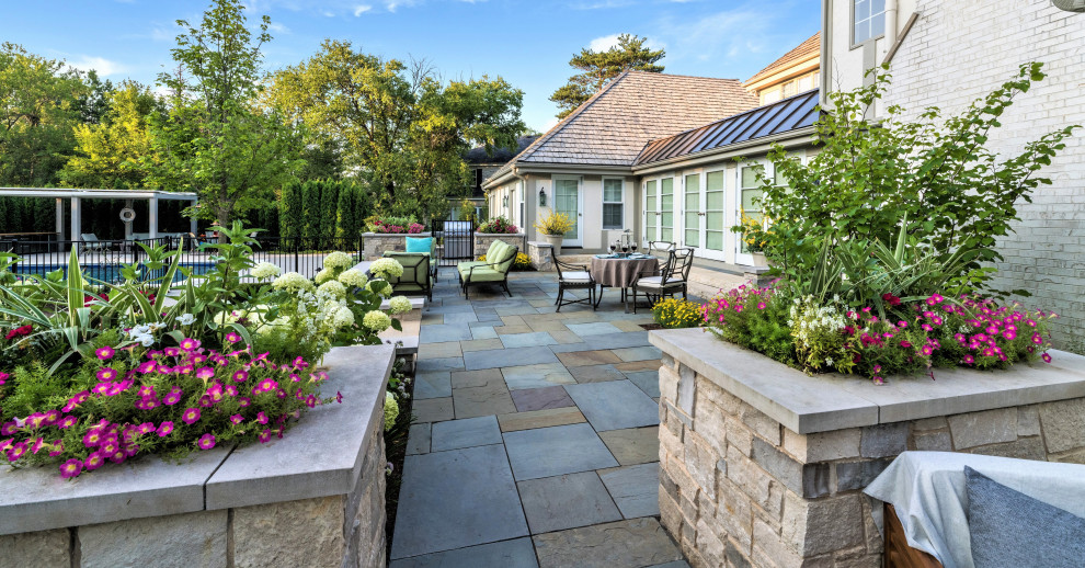 Large traditional backyard patio in Chicago with natural stone pavers and no cover.