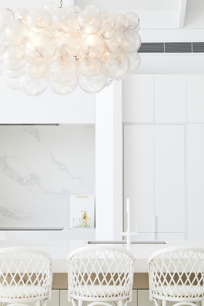 This is an example of a large beach style galley eat-in kitchen in Sydney with an undermount sink, white cabinets, white splashback, panelled appliances, with island and white benchtop.